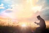 Momen ketenangan saat seseorang berdoa di tengah sinar mentari pagi.