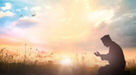 Momen ketenangan saat seseorang berdoa di tengah sinar mentari pagi.
