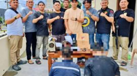 Petugas kepolisian membawa dua pelaku perakitan senjata api ilegal beserta barang bukti yang disita dari rumah warga.