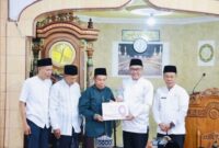 Wako Alfin menyerahkan bantuan secara simbolis kepada pengurus Masjid Madaniatul Islamiyah saat Safari Jum’at di Desa Sumur Anyir.