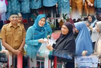 Ketua TP PKK Sri Kartini Alfin bersama Disperindag menyerahkan paket sembako kepada warga dalam kegiatan pasar murah di Sungai Penuh.