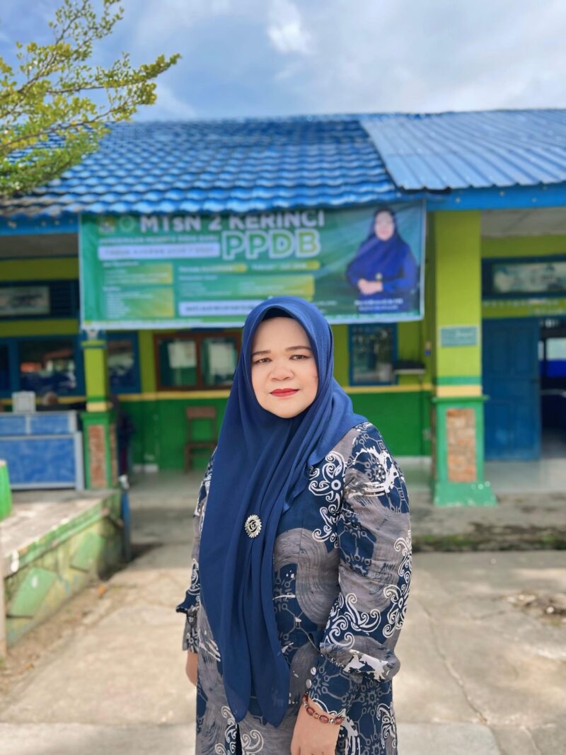 Kepala MTsN 2 Kerinci, Dra. Hj. Niswarti, M.Pd.I, berpose di halaman madrasah yang menjadi lokasi pembangunan gedung serba guna dari infak siswa dan dukungan guru.