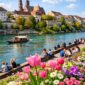 Pemandangan musim semi di Basel, Swiss yang dipenuhi bunga dan wisatawan menikmati suasana kota.
