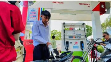 Petugas SPBU melayani pengisian BBM kepada pengendara.
