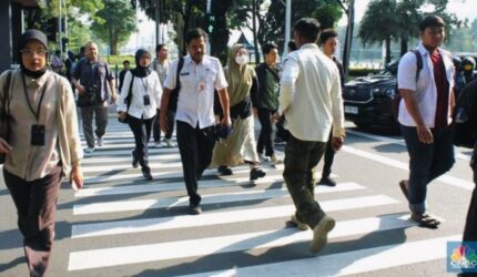 ASN berjalan menuju kantor pada pagi hari di kawasan perkantoran pemerintah