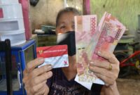 Seorang warga menunjukkan Kartu Keluarga Sejahtera (KKS) dan uang bantuan sosial yang diterima dari program pemerintah.