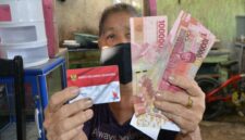 Seorang warga menunjukkan Kartu Keluarga Sejahtera (KKS) dan uang bantuan sosial yang diterima dari program pemerintah.