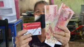 Seorang warga menunjukkan Kartu Keluarga Sejahtera (KKS) dan uang bantuan sosial yang diterima dari program pemerintah.