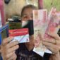 Seorang warga menunjukkan Kartu Keluarga Sejahtera (KKS) dan uang bantuan sosial yang diterima dari program pemerintah.